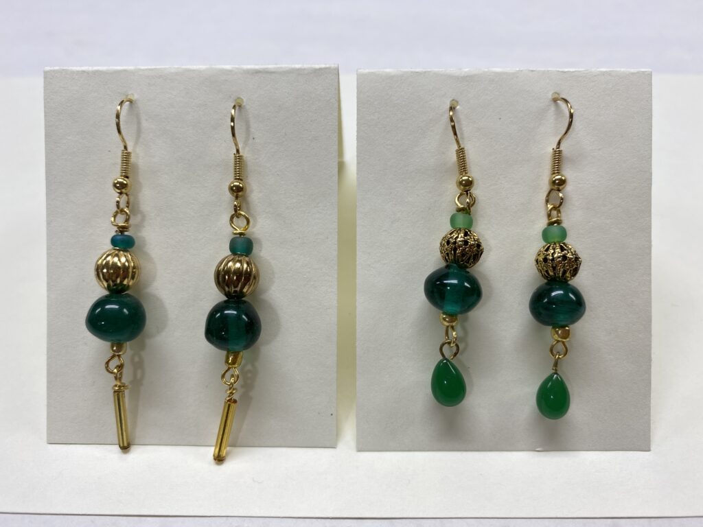 Two sets of gold and green earrings displayed on cards